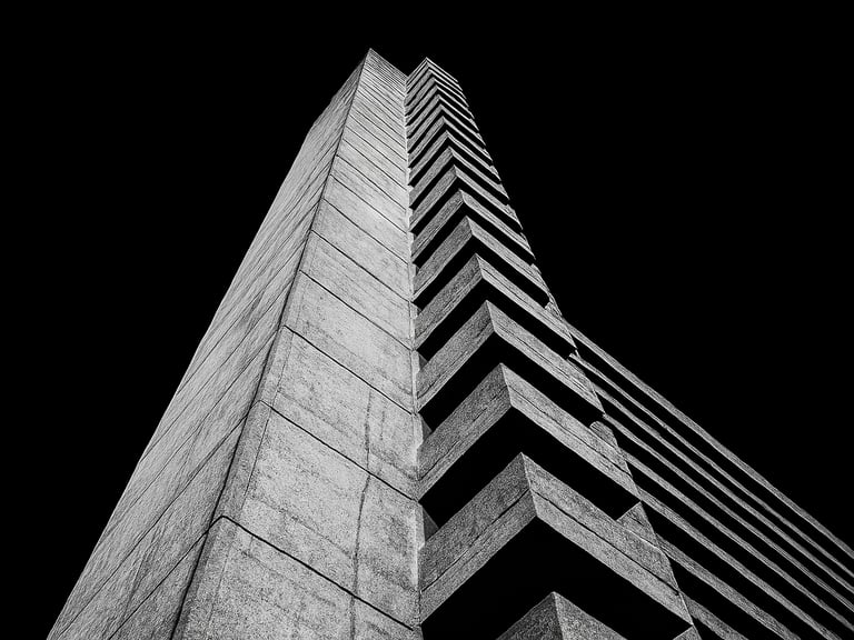 Extreme low-angle shot of a brutalist concrete tower in London, harsh direct flash, deep black sky, high contrast, black and white