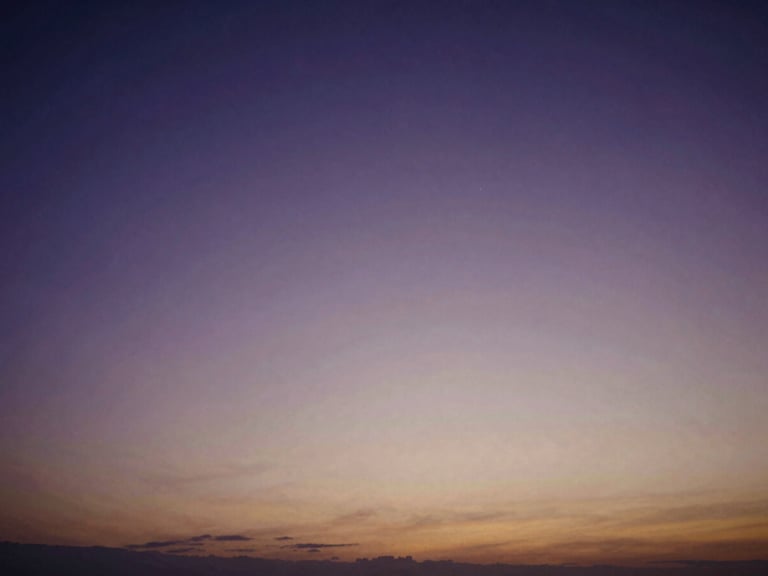 Extreme wide angle twilight landscape, deep violet sky with a faint warm amber glow on the horizon, soft focus 35mm film photography, expansive negative space.
