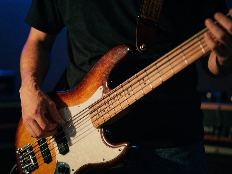 Extreme close-up of hands playing a vintage bass guitar, warm tungsten glow highlighting the strings, dark moody background with 35mm film grain.