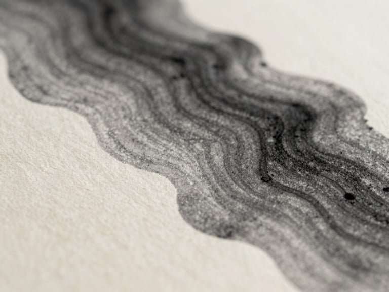 Extreme macro close-up of charcoal black ink bleeding into warm off-white paper fibers, showing rich texture and soft organic gradients under diffused natural daylight