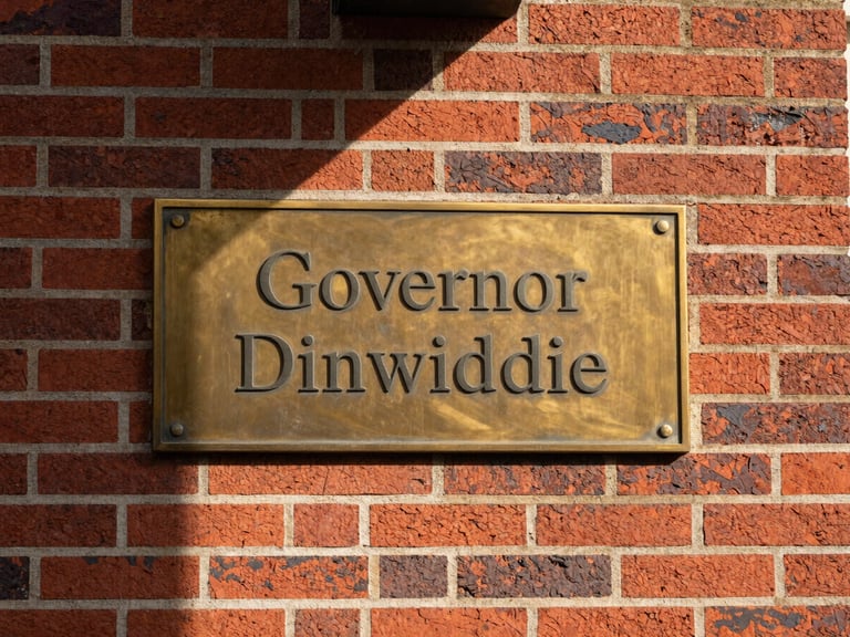 Close-up architectural detail of historic red brickwork and polished brass plaque reading Governor Dinwiddie, soft morning shadows, stately corporate aesthetic, 35mm