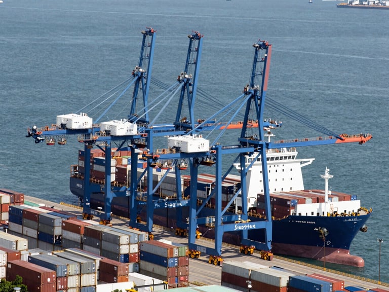 High-angle architectural shot of a massive deep-water shipping terminal in Hong Kong, towering blue container cranes, crisp daylight, slate gray tones.