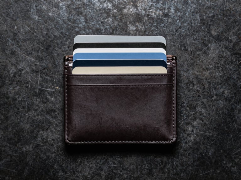 Overhead macro flat-lay of a minimalist wallet stuffed with ten cards, showing its incredibly slim profile against a dark textured steel background.