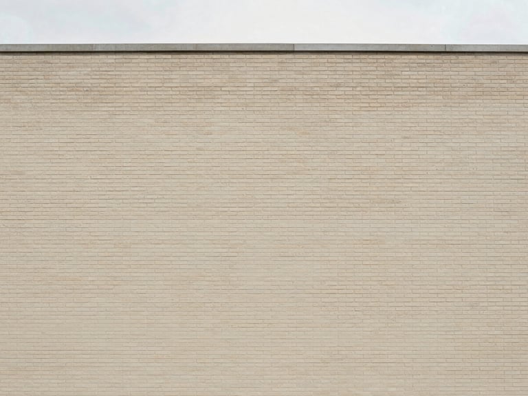 Straight-on architectural lines of a clean brick building facade, soft natural overcast daylight, muted warm neutral tones.