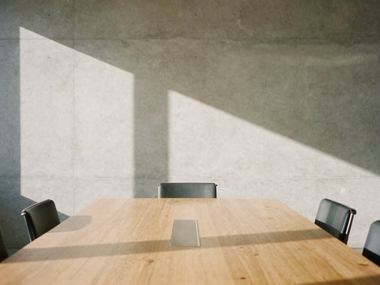 Architectural detail of a clean modern boardroom in Newhall, bright California daylight casting long shadows on a concrete wall, minimal aesthetic, 35mm