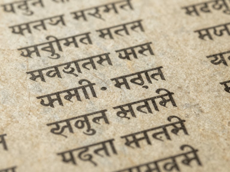 Close-up of ancient textured paper with faded Sanskrit manuscripts, soft diffused library light, archival editorial photography