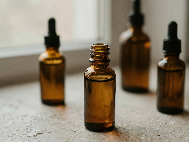 Close-up of botanical massage oils in amber glass bottles on a textured stone surface, soft diffused window light, muted earth tones.