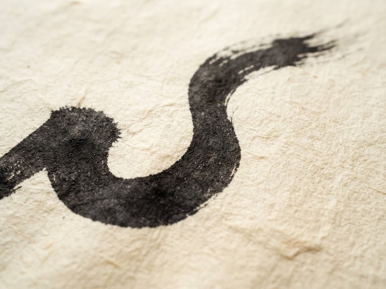 Macro detail of a single bold calligraphic stroke on textured ivory handmade paper, soft natural side-light, minimal composition