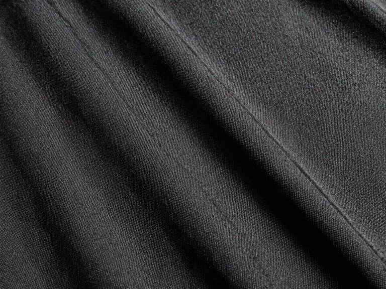 Close-up of heavy-gauge black canvas fabric, showing tight weave and raw texture, under harsh direct daylight, high contrast, 35mm film, sharp focus.