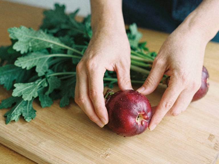 Hands carefully arranging fresh produce on a wooden board, soft natural light, shallow depth of field, rich crimson and forest green tones