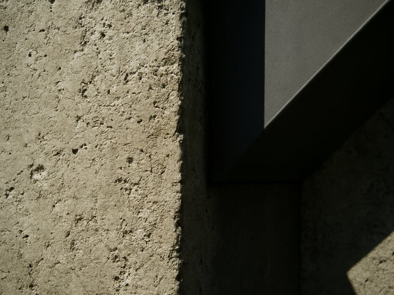 Close-up of raw construction materials, textured poured concrete meeting a clean steel joint, high-contrast natural sunlight casting sharp geometric shadows.