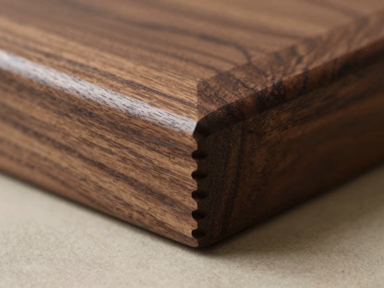 Macro close-up of a splined corner joint on a dark walnut frame, natural side-light highlighting the precise wood grain and hand-planed finish
