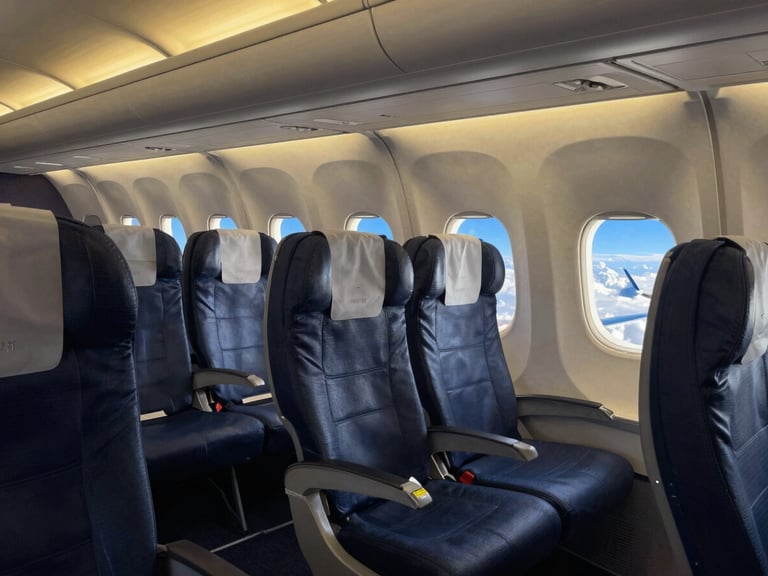 Intérieur moderne d'un avion avec des sièges confortables et un hublot montrant un ciel bleu, éclairé par une lumière douce et chaude.