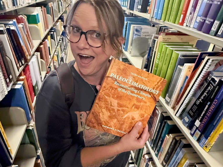 A picture of Jess Newman in a library holding a book with excitement