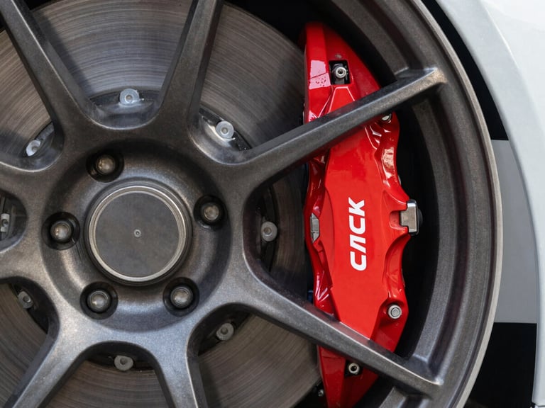 Extreme close-up of a high-performance red brake caliper behind a dark titanium multi-spoke wheel, clean studio lighting, sharp focus