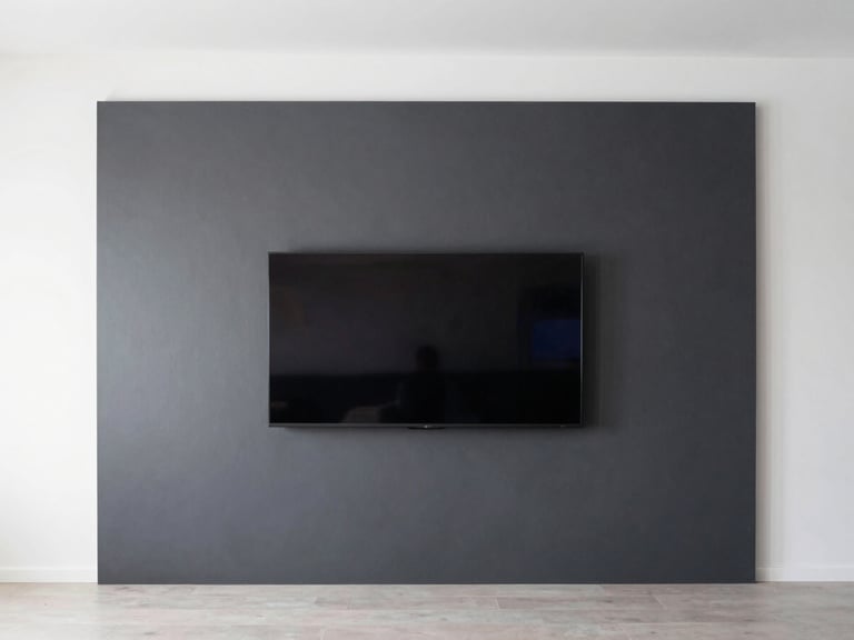 Wide shot of a minimalist living room, a perfectly flush-mounted flat screen TV on a charcoal accent wall, zero visible wires.