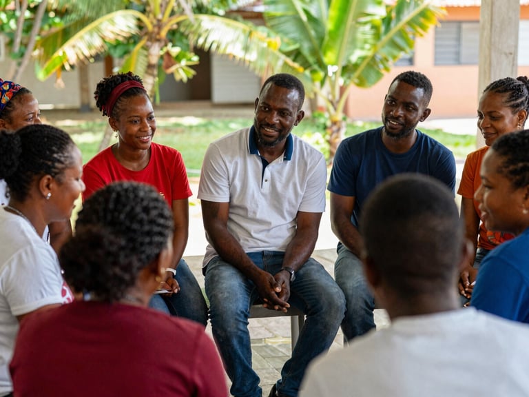 Candid medium shot of Haitian teachers engaged in a training session, collaborating and smiling, natural Caribbean sunlight, rich organic tones, 35mm