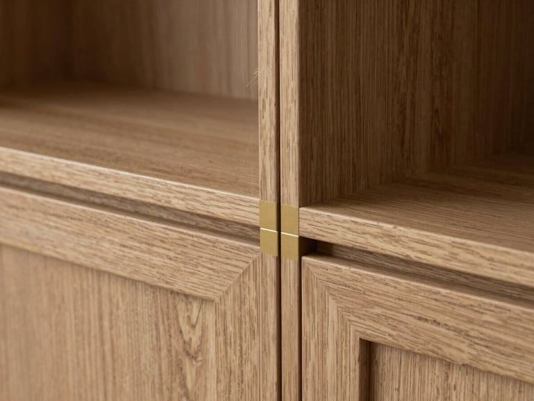 Architectural close-up of custom kitchen cabinetry joint, natural oak grain matching perfectly with a thin gold metal inlay, soft side lighting.
