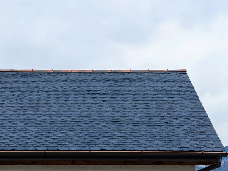 Architectural close-up of a perfectly aligned slate roof with copper gutters, soft overcast Swiss sky, sharp focus