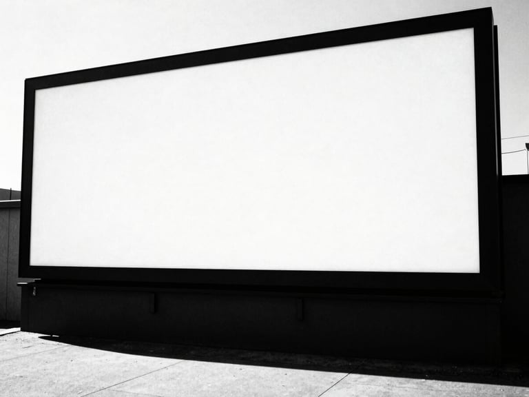 Wide environmental shot of a large-scale outdoor advertising billboard in an urban setting, bathed in harsh direct sunlight, casting a long, sharp shadow. High-contrast black and white photography, sharp focus, 35mm film grain.