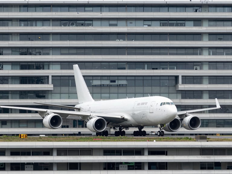 High-capacity cargo aircraft on a runway at an international airport under overcast daylight, wide-angle architectural framing, cool industrial photography, desaturated steel tones, sharp focus, 35mm