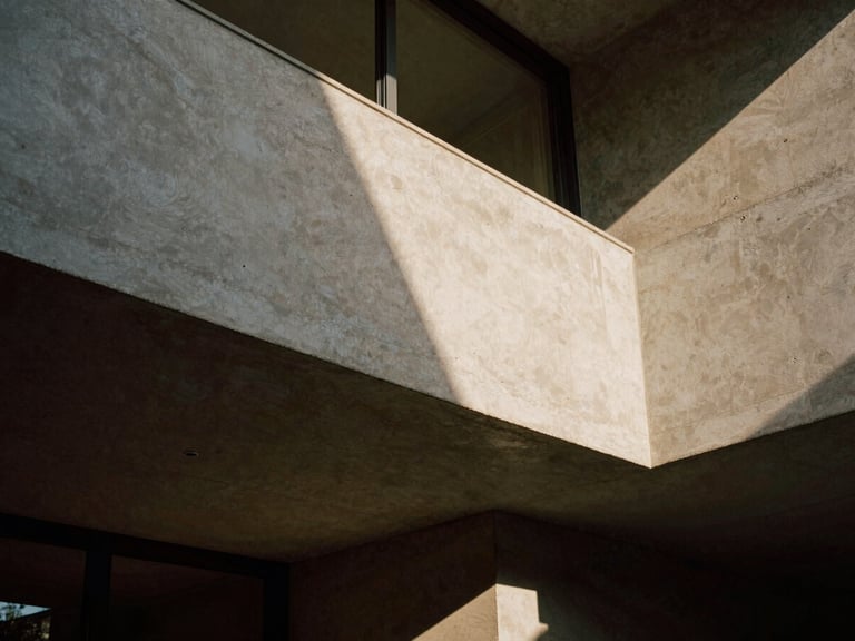 Dramatic architectural elevation of a concrete and travertine residential interior, sharp low-angle window light casting long shadows, medium format film
