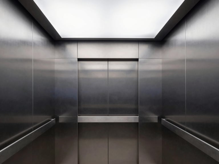 Interior of a clean modern elevator cabin, brushed steel panels, minimalist LED ceiling lighting, sharp architectural framing
