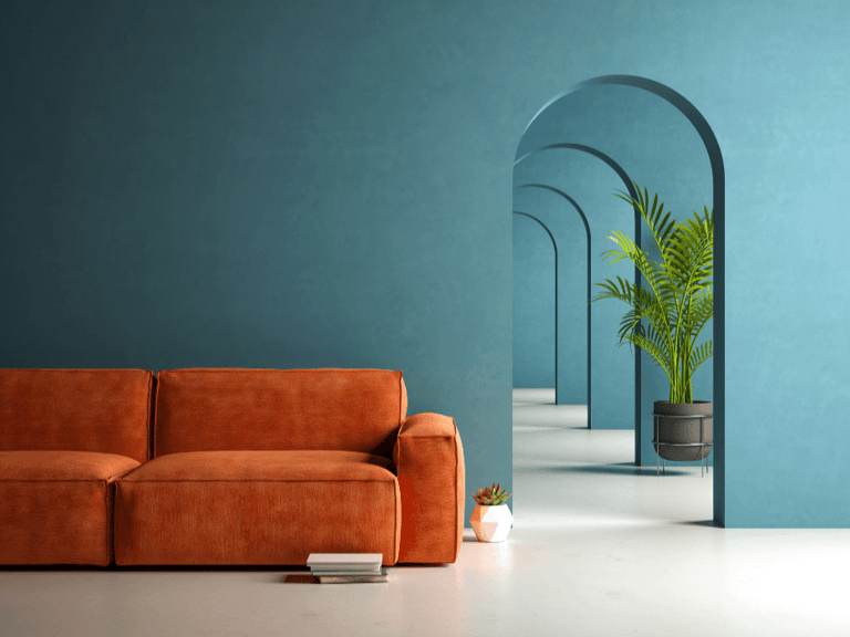 Modern living room with orange velvet sofa against a teal wall and arched hallway.