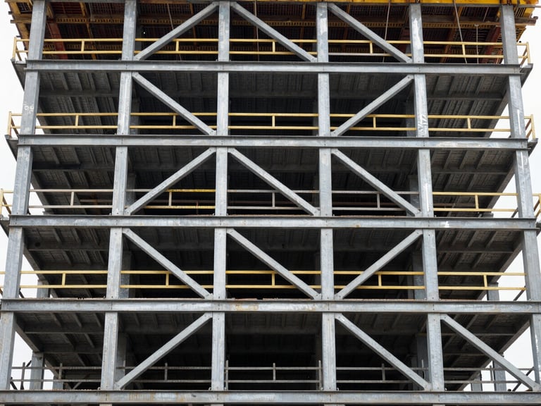 Industrial documentary photography, straight-on wide shot of a structural steel elevator shaft under construction, natural high-contrast site lighting, cool steel tones, 35mm