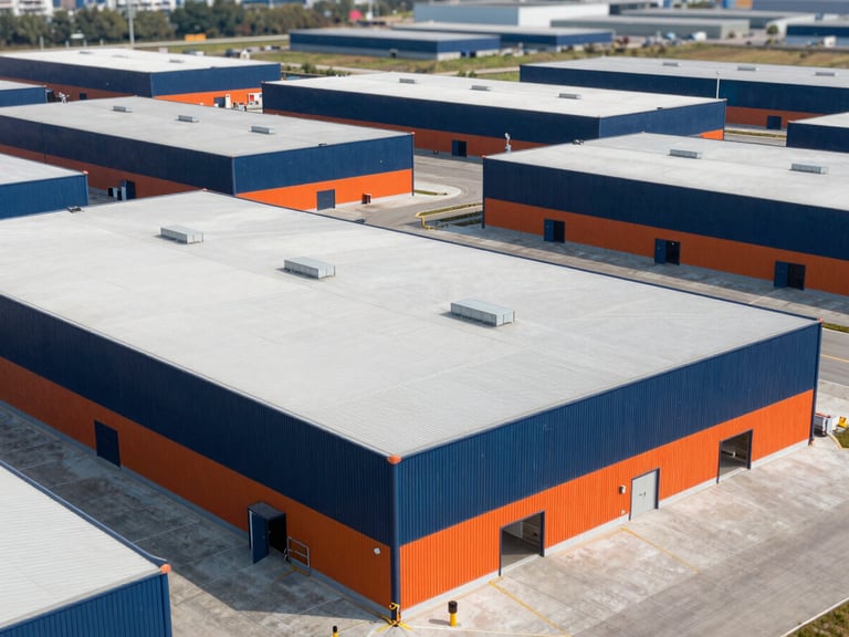 Clean aerial shot of a modern industrial park with several large warehouses under bright natural daylight, crisp industrial photography, high-contrast navy and safety orange tones, sharp focus, 35mm.