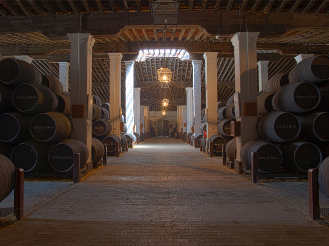 Historic Spanish sherry bodega with rows of stacked oak wine barrels in a traditional cellar.