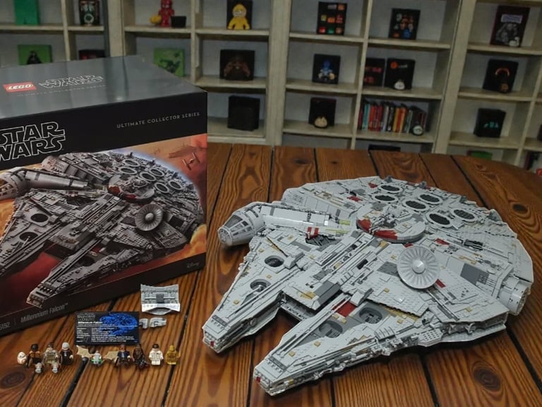 Vue d'ensemble du Faucon Millenium LEGO UCS 75192 avec l'équipage complet des deux trilogies et son emballage imposant.