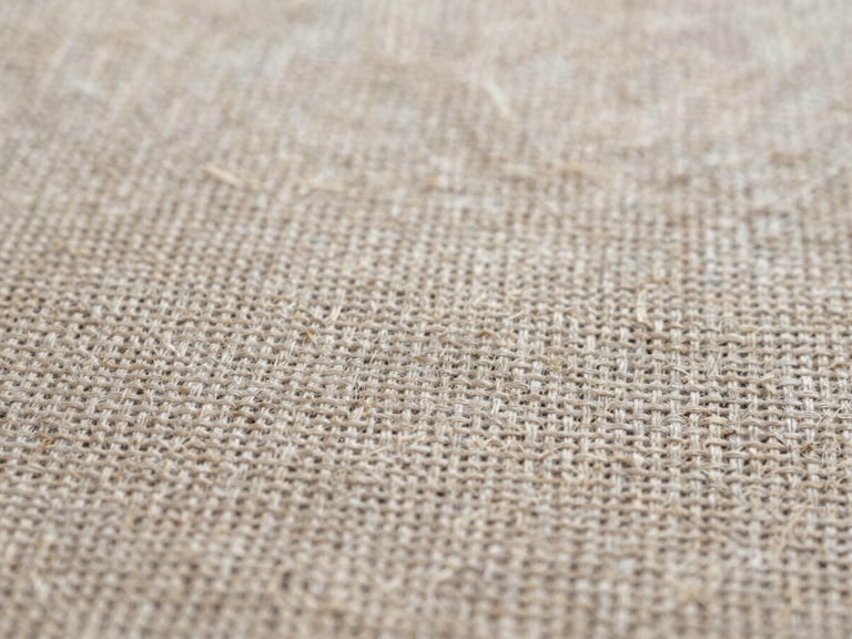 Tactile textile photography, extreme close-up of natural raw linen fabric weave, diffused daylight, neutral earth tones, high detail texture, 35mm