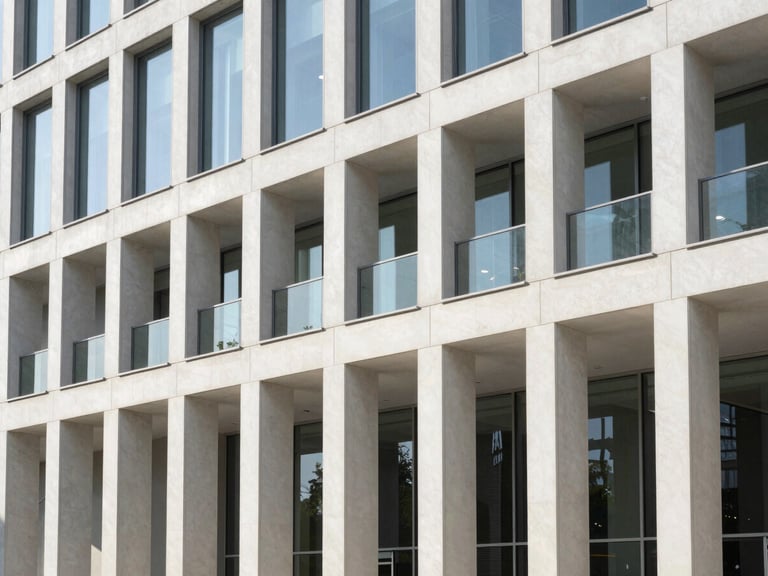 Bright editorial photography of a sunlit modern office building facade with clean architectural lines, morning sun, 35mm
