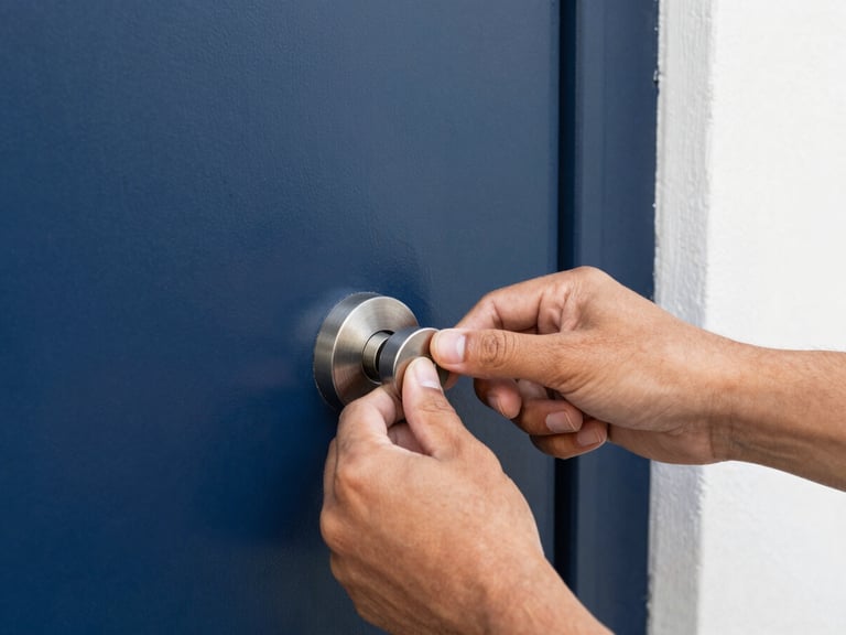 Close-up of professional hands installing a heavy-duty deadbolt on a modern front door, bright daylight, crisp focus, rich navy and orange tones