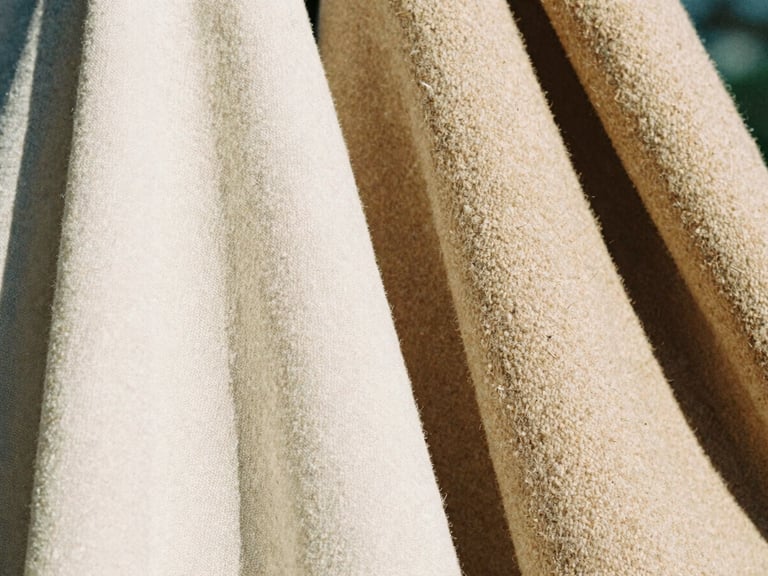 Extreme close-up of heavy-weave cream linen and soft beige wool draped together, showing rich fabric textures under warm natural morning light, 35mm film