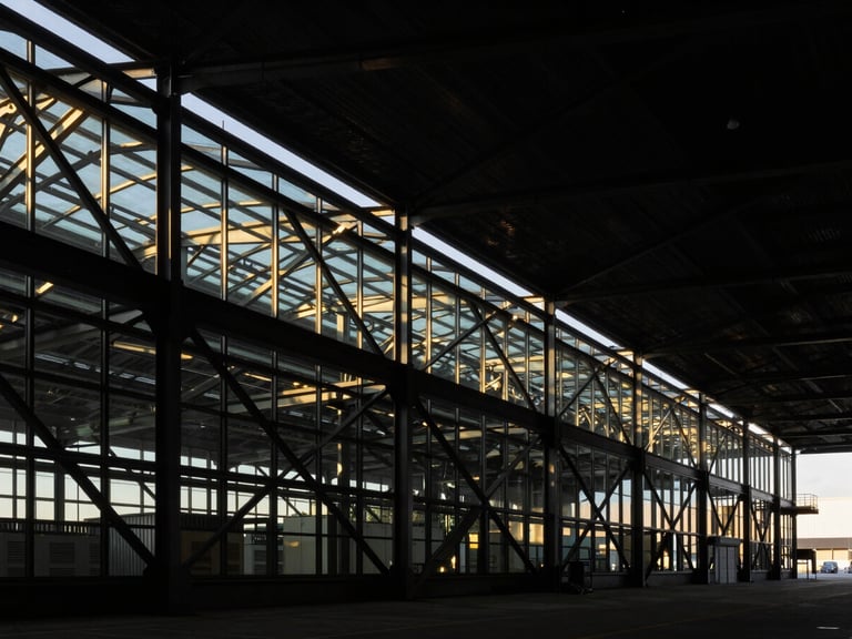 Abstract geometric structure of a modern steel and glass logistics terminal, high-contrast architectural lighting, dramatic shadows, sharp focus.