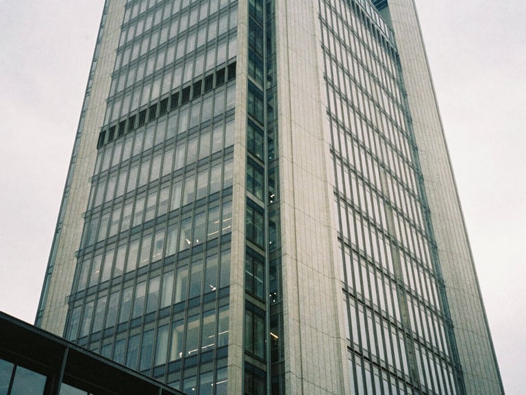 Architectural detail of a modern skyscraper in Frankfurt, low-angle shot, soft diffused daylight, steel and glass textures.