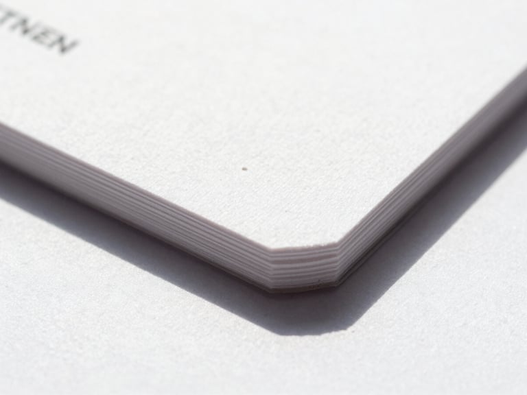 Macro detail shot of freshly printed thick cotton business cards with deep ink saturation, crisp edges, natural daylight casting soft shadows, showing tactile paper texture.