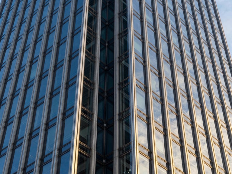 Dramatic close-up of structural glass joints on a commercial skyscraper facade, reflecting the blue sky, silver-blue metallic mullions, millimeter precision alignment