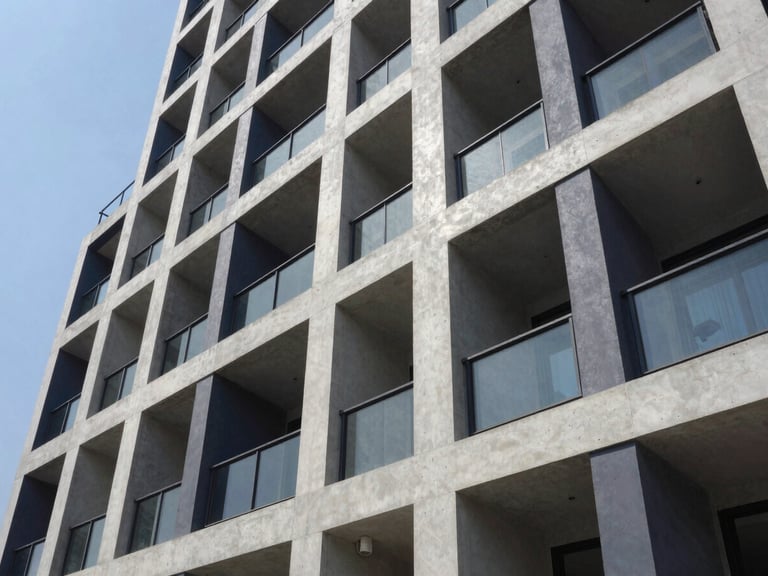 Sharp architectural exterior shot of a modern residential building in Dhaka, concrete gray and deep navy tones, crisp daylight, high-contrast shadows