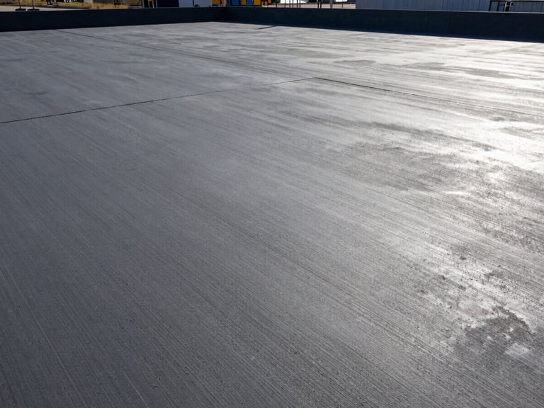 Wide shot of a completed, smooth-troweled concrete slab at the Riverbend Logistics Hub, high-contrast morning light, industrial setting, 35mm lens.