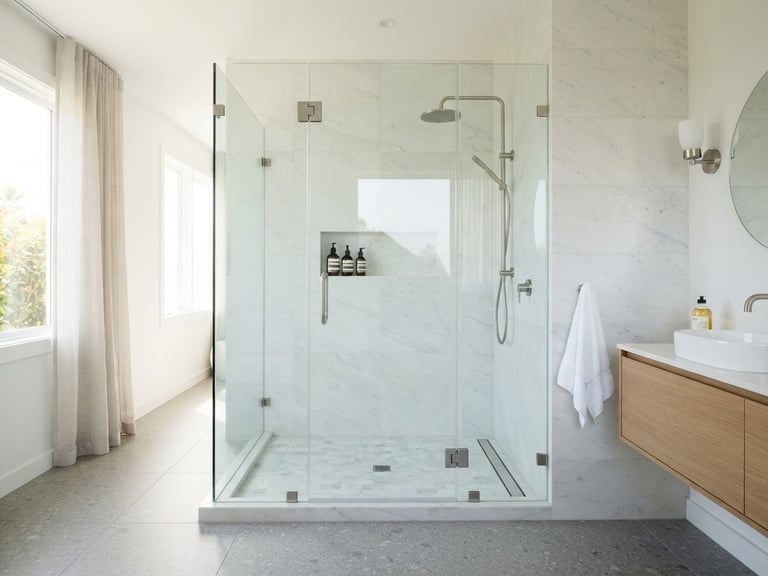 Straight-on architectural photography of a minimalist frameless glass shower enclosure in a bright, modern bathroom, natural daylight, crisp reflections, neutral tones, 35mm lens