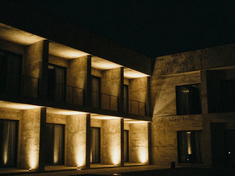 Architectural elevation of a concrete hotel courtyard at night, precise narrow beams of warm light on columns, dark sky, grainy texture