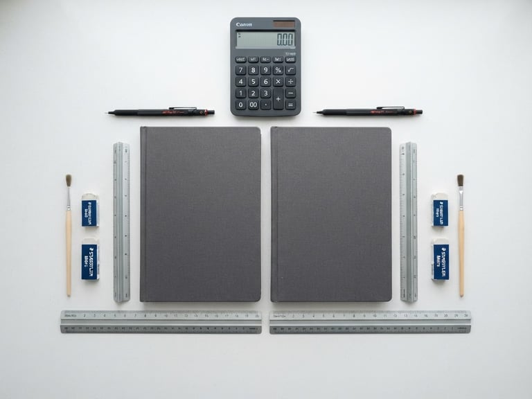 Symmetrical flat-lay of financial ledgers, a sleek modern calculator, and technical drafting tools on a clean white desk, bright overcast daylight, sharp focus