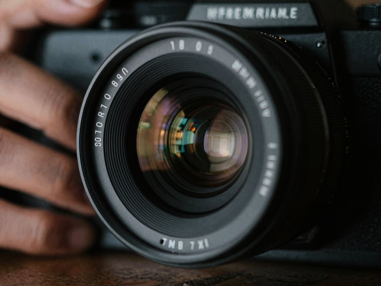 Close-up of a physical 35mm camera lens, reflection of set lights in the glass, hands adjusting focus, low-key dramatic lighting
