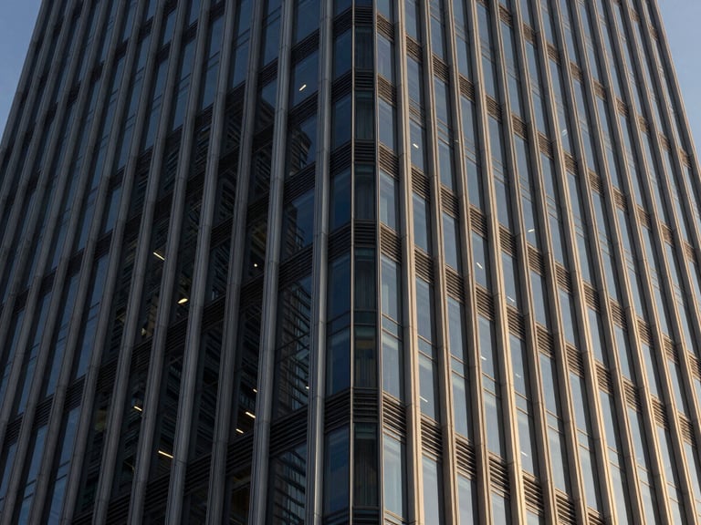 Abstract architectural close-up of a modern steel and glass skyscraper facade, sharp late-afternoon shadows, deep navy tones