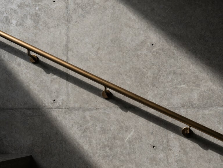 Close-up architectural photography of a minimalist concrete wall with a bespoke bronze handrail, dramatic side-lighting