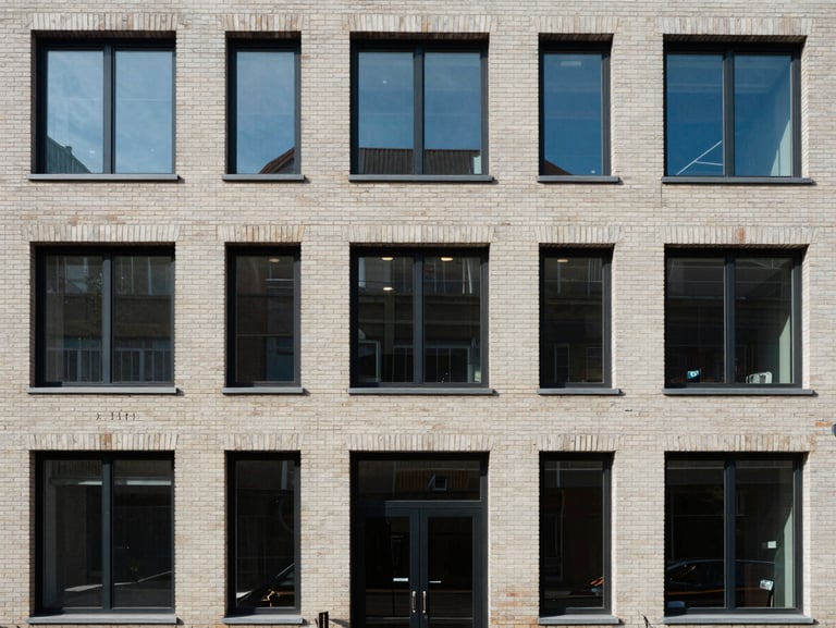Close-up of a residential building facade straight-on, clean brick and glass exterior, north-facing flat light, no people, architectural detail of windows and entry door visible, urban street edge at bottom of frame