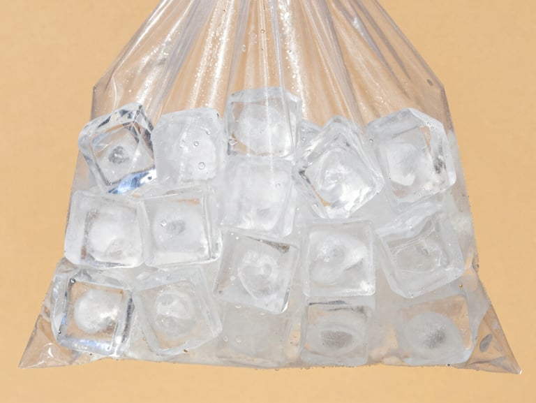 A heavy-duty clear bag filled with large, completely cloud-free crystal-clear ice cubes sweating under bright summer sun, warm-toned background